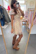 Load image into Gallery viewer, Woman taking a mirror selfie wearing a floral dress and brown boots in a clothing store.
