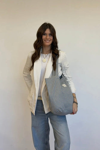 Woman holding a checkered bag against a plain background