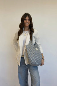 Woman holding a checkered bag against a plain background