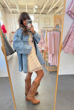 Load image into Gallery viewer, Person taking a mirror selfie wearing a blue coat, floral dress, and brown boots in a clothing store.