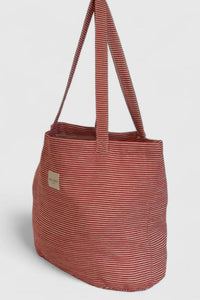 Striped tote bag with a visible brand label on a light gray background