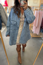 Load image into Gallery viewer, Person wearing a denim jacket and floral dress with brown boots in a clothing store.