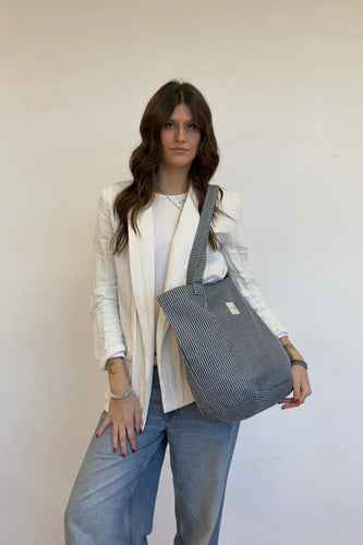 Woman holding a gray striped bag against a white background