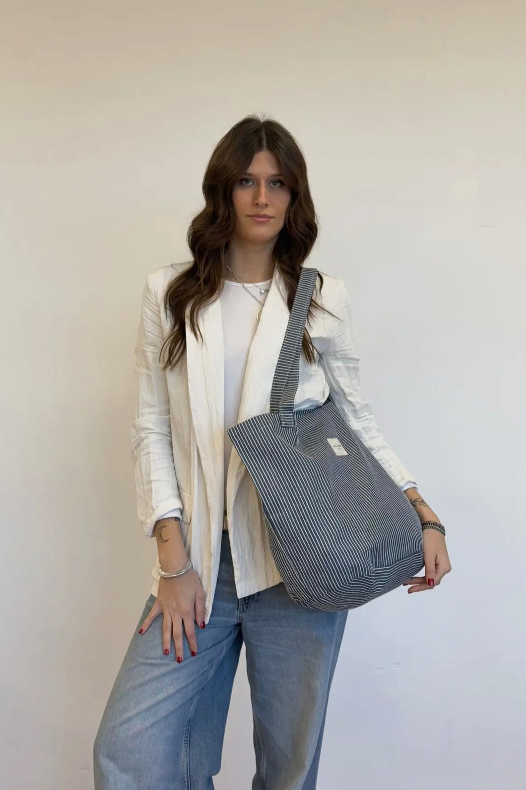 Woman holding a gray striped bag against a white background