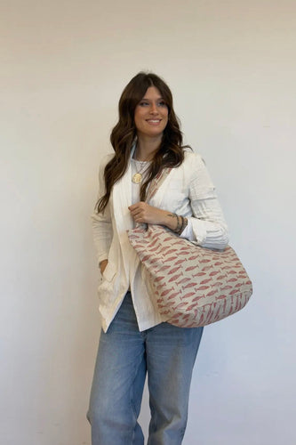 Woman holding a patterned bag against a plain background