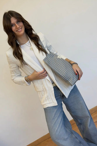 Woman holding a checkered handbag against a plain background