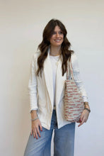 Load image into Gallery viewer, Woman holding a patterned bag against a plain background