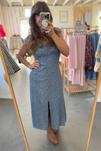 Load image into Gallery viewer, Person wearing a blue floral dress in a clothing store.