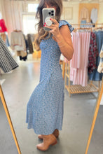 Load image into Gallery viewer, Woman taking a mirror selfie wearing a blue floral dress in a clothing store.