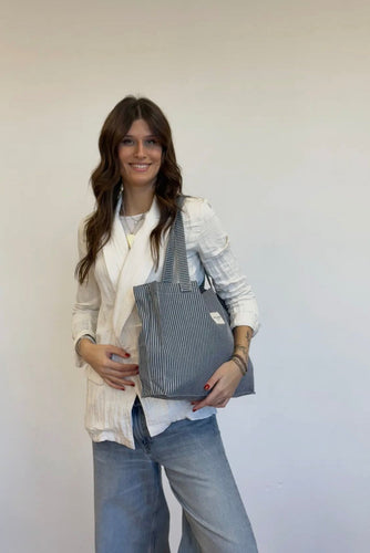 Woman holding a gray tote bag against a white background