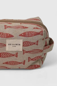 Cosmetic bag with red fish pattern and 'DELA MUR' label on a white background