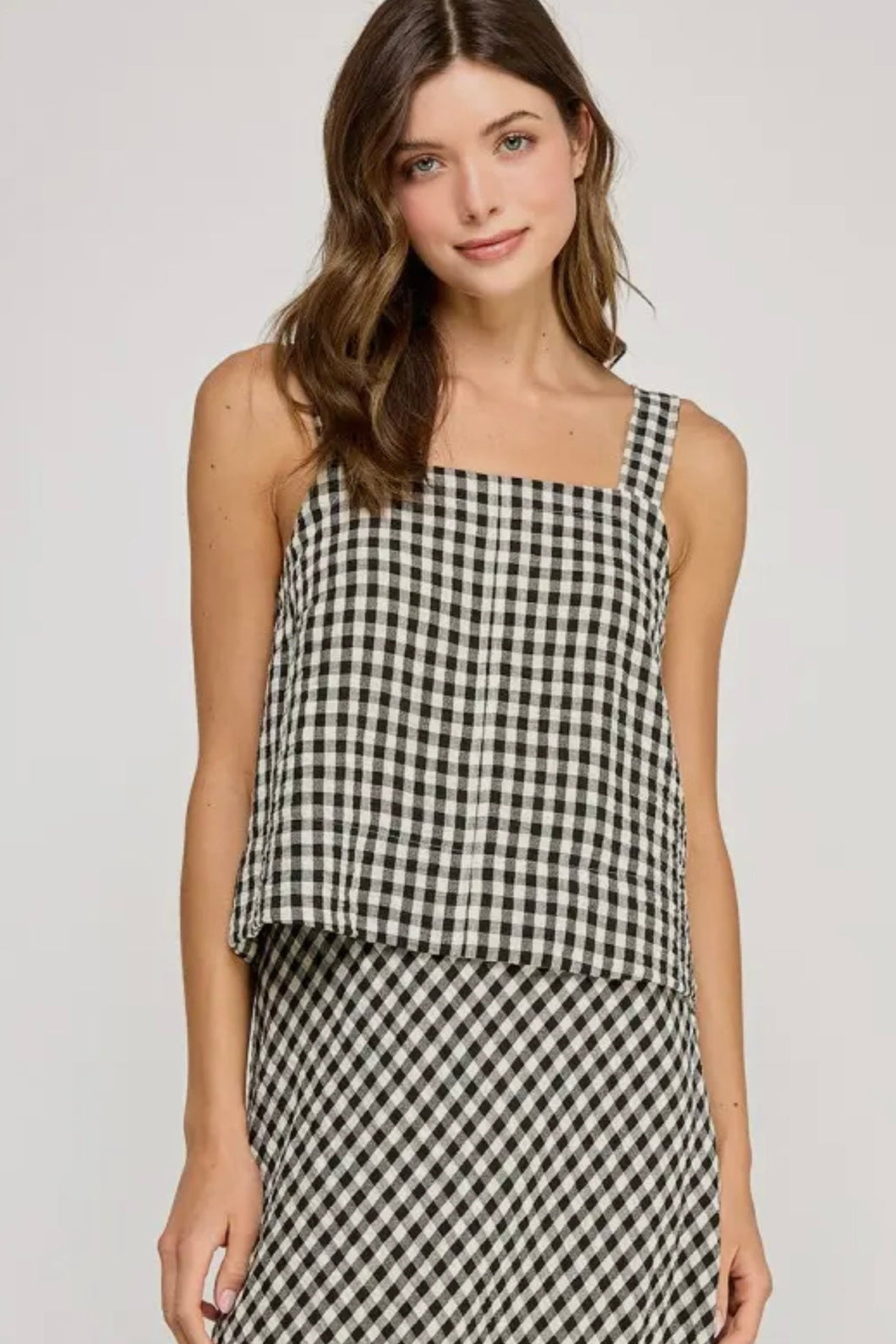 Woman wearing a black and white checkered dress on a plain background