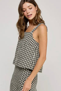 Woman wearing a black and white checkered top and skirt on a plain background