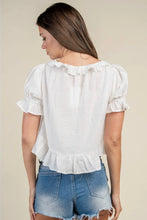 Load image into Gallery viewer, A woman shown from the back wearing a white short-sleeve blouse with ruffled trim and puffed sleeves, paired with blue denim shorts, against a plain beige studio background.