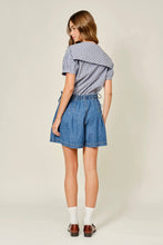 Load image into Gallery viewer, Woman wearing a checkered shirt and denim skirt on a plain background