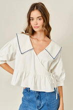 Load image into Gallery viewer, Woman wearing a white blouse with blue trim and blue jeans on a plain background