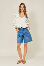 Load image into Gallery viewer, Woman wearing a white blouse with a large collar and blue denim shorts on a plain background