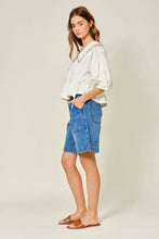 Load image into Gallery viewer, Woman wearing a white blouse and blue denim shorts on a plain background