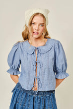 Load image into Gallery viewer, Woman wearing a blue blouse with ruffled collar and sleeves on a beige background