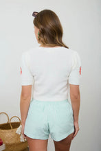 Load image into Gallery viewer, Person wearing a white top and light green striped shorts against a plain background
