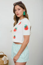 Load image into Gallery viewer, Woman wearing a white top with strawberry designs and light blue shorts, holding a woven bag.