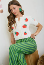 Load image into Gallery viewer, Woman wearing a white blouse with red apple designs and green striped pants against a white background