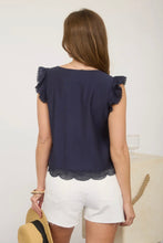 Load image into Gallery viewer, Woman wearing a navy blue top with ruffled shoulders and white shorts against a neutral background