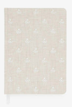 Load image into Gallery viewer, A hardcover notebook with a beige linen-textured cover featuring a repeating white embroidered floral pattern, shown on a clean white background.