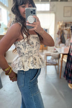 Load image into Gallery viewer, Woman taking a mirror selfie wearing a patterned top and jeans in a store.