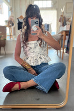 Load image into Gallery viewer, Person sitting on the floor taking a mirror selfie wearing a patterned top, jeans, and red shoes.