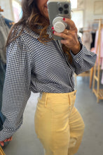 Load image into Gallery viewer, Person wearing a black and white checkered shirt and yellow pants taking a mirror selfie.