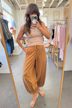 Load image into Gallery viewer, Person taking a mirror selfie wearing a beige tank top and brown pants in a clothing store.
