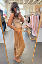 Load image into Gallery viewer, Woman taking a mirror selfie wearing a beige top and brown pants in a clothing store.