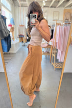 Load image into Gallery viewer, Woman taking a mirror selfie wearing a beige tank top and tan pants in a clothing store.