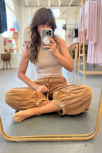 Load image into Gallery viewer, Woman taking a mirror selfie wearing a beige top and tan pants in a store.