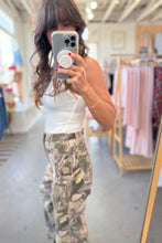 Load image into Gallery viewer, Person taking a mirror selfie wearing a white top and camouflage pants in a store.