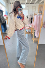 Load image into Gallery viewer, Person wearing a cream sweater with colorful patterns and checkered pants in a clothing store.
