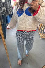 Load image into Gallery viewer, Person wearing a cream sweater with blue fish designs and checkered pants in a store setting.