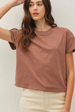 Load image into Gallery viewer, A woman wearing a muted dusty rose short-sleeve crewneck t-shirt and cream-colored pants, photographed against a neutral light gray background.