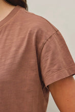 Load image into Gallery viewer, Close-up of a person wearing a short-sleeve crew-neck t-shirt in a dusty rose or mauve color, showing the fabric texture and sleeve construction against a plain light background.