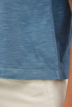 Load image into Gallery viewer, Close-up of a person wearing a heathered blue short-sleeve top and light beige shorts, showing the fabric texture and hem.