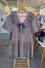 Load image into Gallery viewer, Checkered dress with ruffled collar and sleeves on a hanger in a store setting.