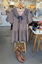 Load image into Gallery viewer, Checkered dress with a bow and brown boots on a stand in a store setting
