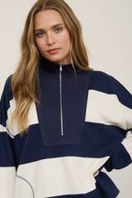 Load image into Gallery viewer, A woman wearing a navy blue and off-white color-blocked half-zip sweatshirt, photographed against a plain light beige studio background.