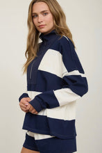 Load image into Gallery viewer, A woman wearing a navy blue and white color-blocked quarter-zip sweatshirt and matching shorts, photographed against a plain light gray studio background.