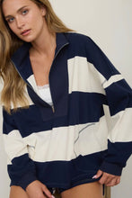 Load image into Gallery viewer, A woman wearing an oversized half-zip sweatshirt with bold horizontal navy blue and off-white stripes, photographed against a plain light background.