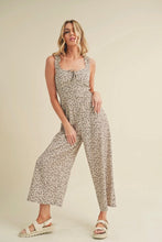 Load image into Gallery viewer, Woman wearing a floral jumpsuit on a beige background
