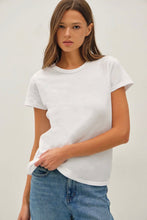 Load image into Gallery viewer, A woman wearing a plain white short-sleeve crewneck t-shirt and blue jeans, standing against a light gray studio background.