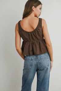 Woman wearing a brown checkered top and blue jeans on a plain background