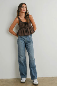 Woman wearing a brown top and blue jeans against a plain background